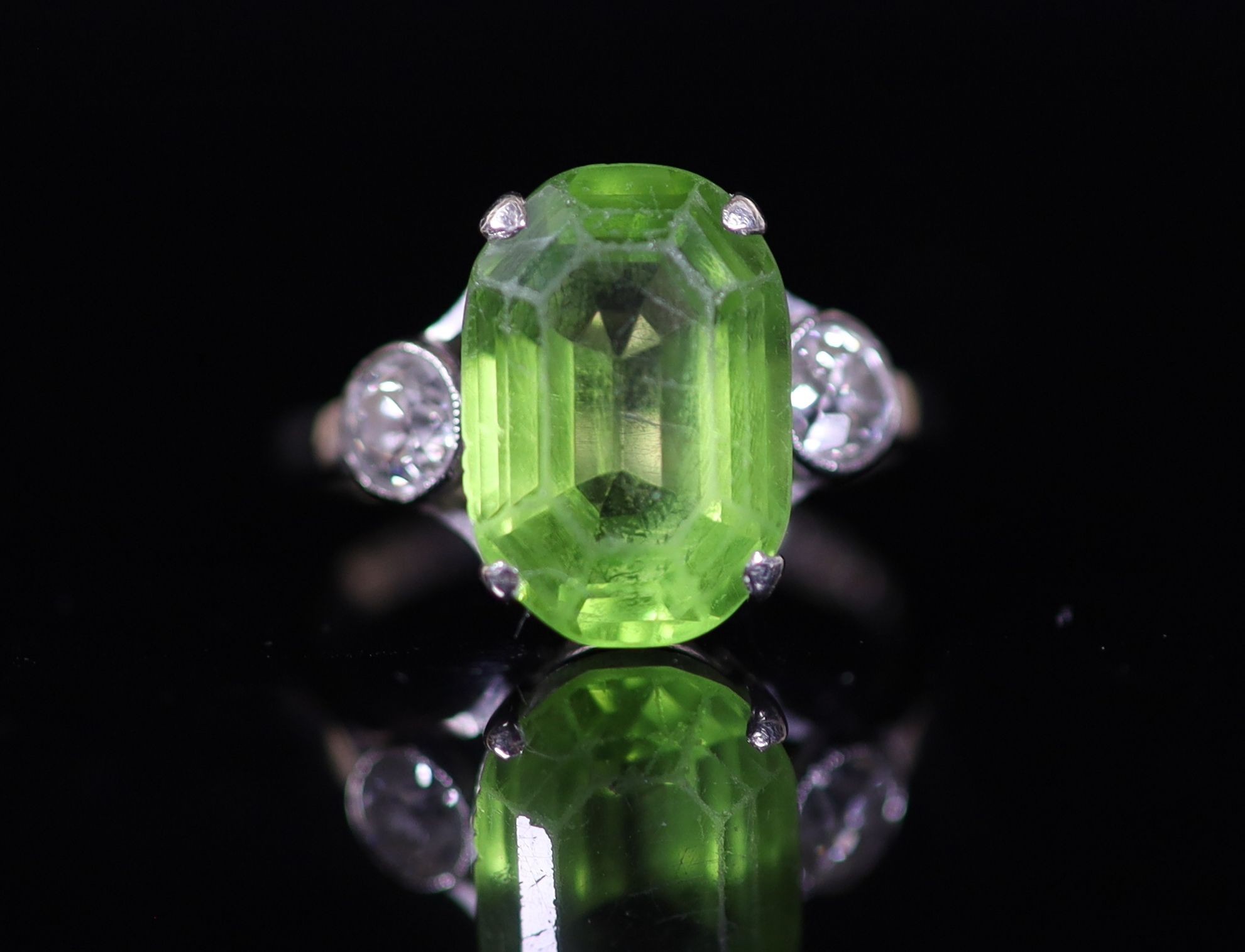 A 9ct white gold oval cut peridot set dress ring, with diamond set shoulders